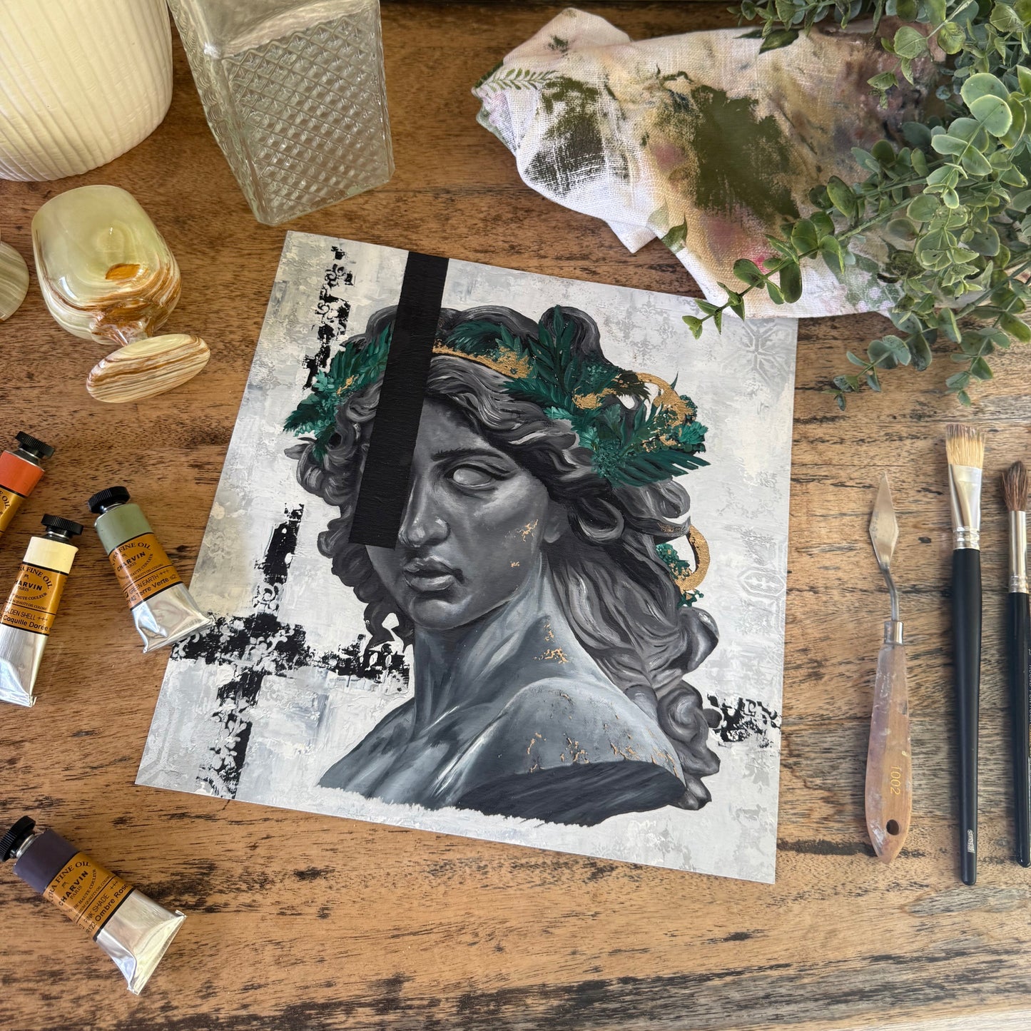 Artistic depiction of a face with nature elements on a wooden surface with art supplies.  By Kendelle Ashton.  Fine art print